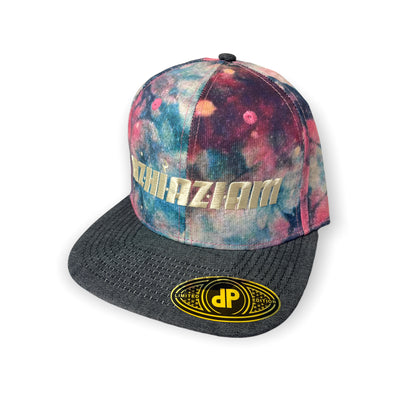 A photo of Azhiaziam's Denim Tye Dye Hat featuring a tie-dye pattern on a denim fabric. The hat has a flat bill and an adjustable snap back closure. Cream embroidered "Azhiaziam" on front panel.
